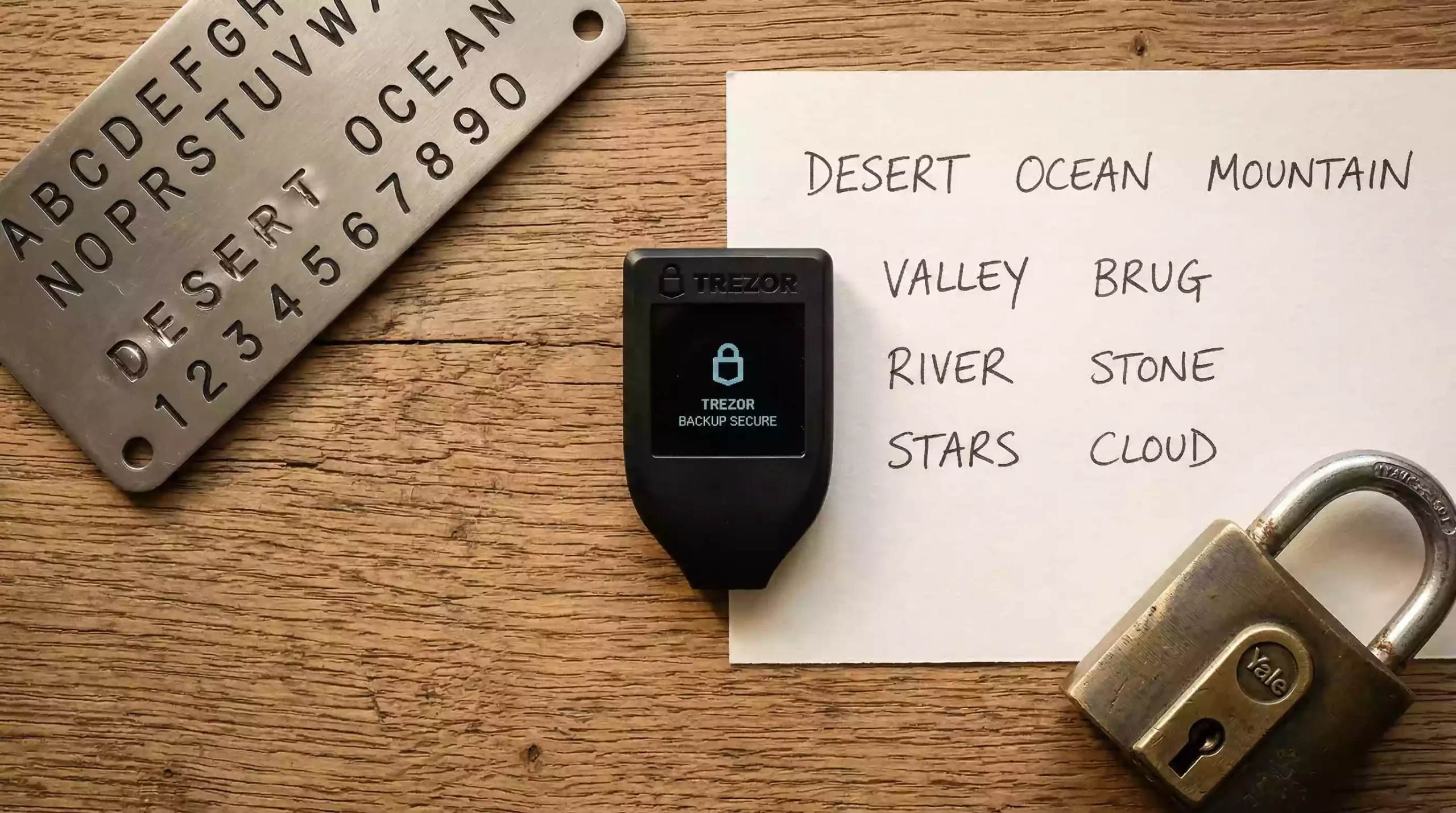 Hardware wallet Ledger accanto a un foglio con seed phrase scritta a mano su una scrivania in legno